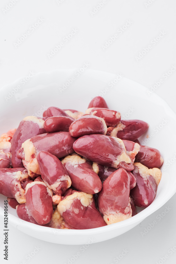 raw chicken hearts in a white plate on a white background. Close-up. 