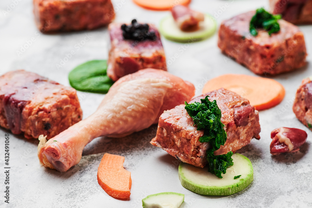 Composition with raw square cutlets and raw chicken legs on a light background. Natural dog food. 