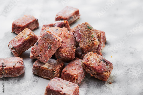 Composition with raw square cutlets on a light background. Natural dog food. Diet for dogs BARF. Close up