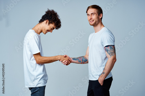 two friends hold hands in white t-shirts isolated background