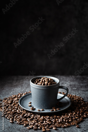 Gray cup full of coffee beans on a dark gray stone background