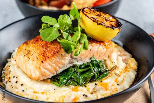 Foto A seafood dinner serve of a piece of Salmon on top of mashed potatoes, in a dark