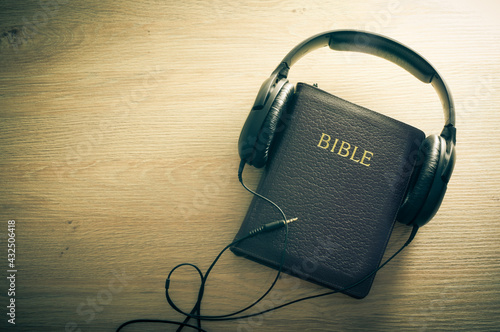 Bible and headphones on wooden background with copy space