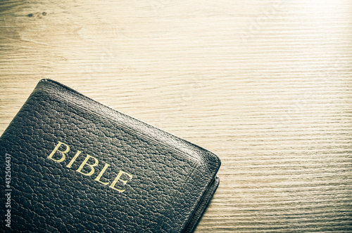 Bible and paper on wooden table background with large copy space