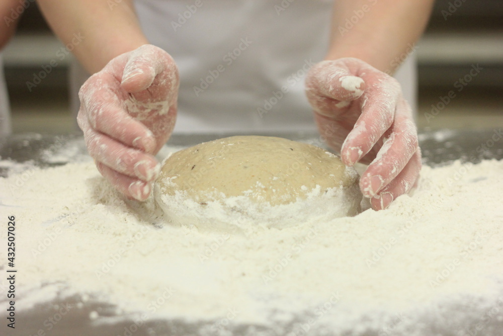 Obraz premium Woman's hands kneading the bread dough. Making dough by female hands on wooden table