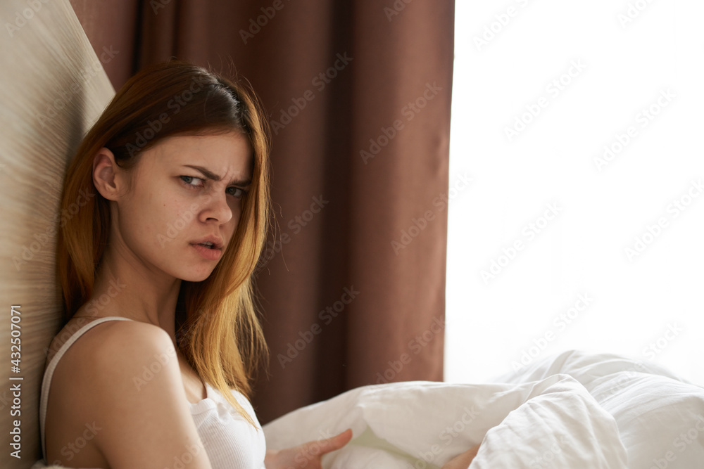 Fototapeta premium upset woman under blanket bed and open window curtains model side view