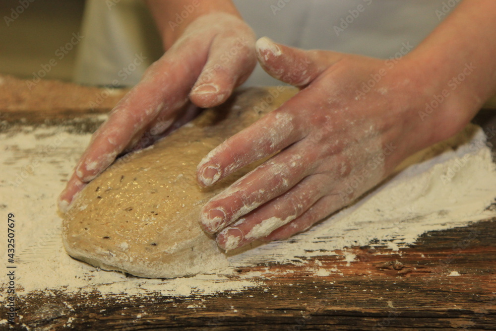 Woman's hands kneading the bread dough. Making dough by female hands on wooden table