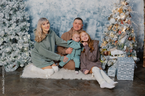 Beautiful and happy family at the New Year tree at a photo shoot.