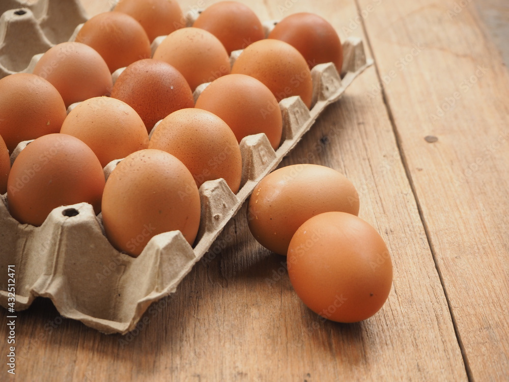 Brown chicken eggs close-up in carton box on the wooden table with text area space, wooden background. Brown chicken eggs close-up in carton box on the wooden table with text area space, wooden background.