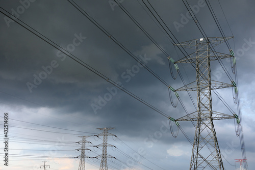 Canvas Print Several electrical transmission towers and high voltage wires with a stormy sky,