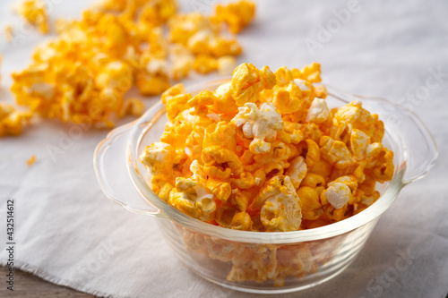 Caramel popcorn in glass bowl on wooden table background