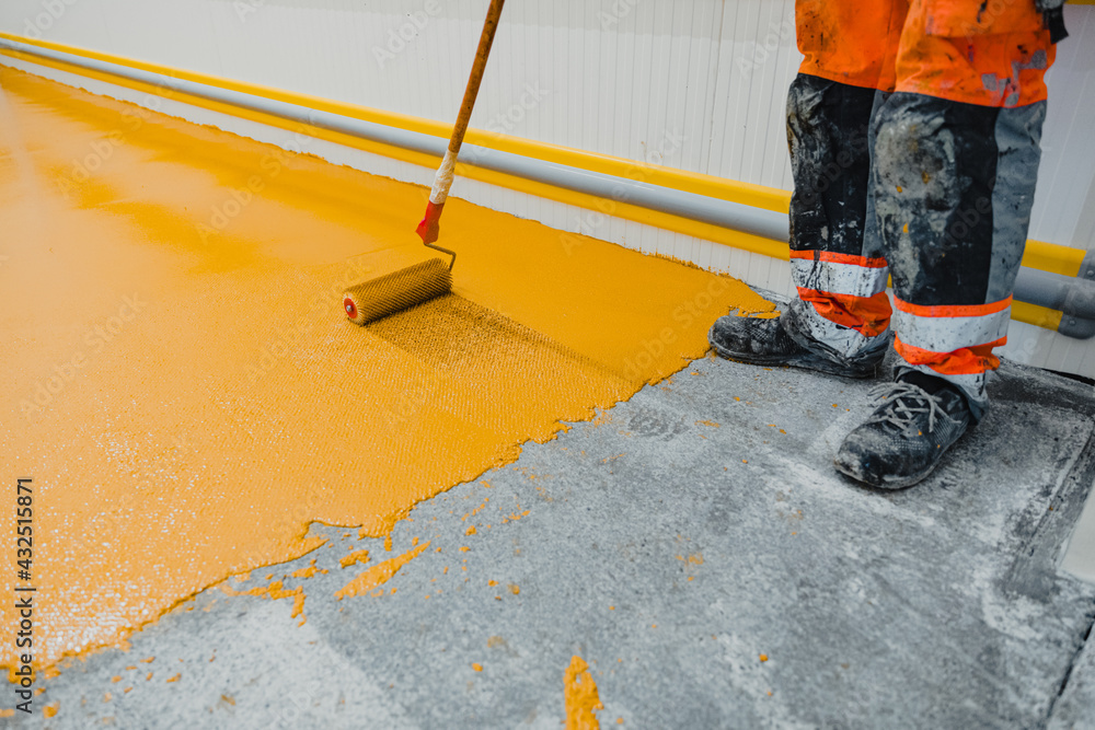 Worker applying epoxy and polyurethane flooring system