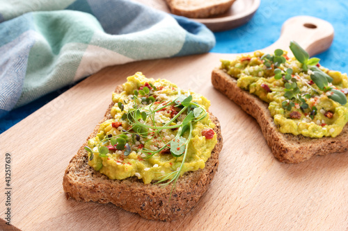 Two toasts with avocado, microgreens and hemp seeds on a wooden kitchen board
