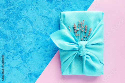 Gift wrapping Japanese furoshiki style on a blue and pink background.