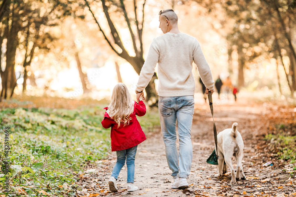 Obraz premium Happy beautiful family with dog labrador is having fun together walking the in park.