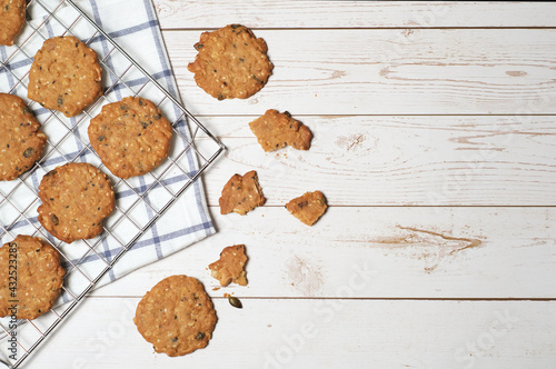 Pumpkin seed and sesame cookie on cooling rack and napkin on white wooden background with coppy space on right. photo