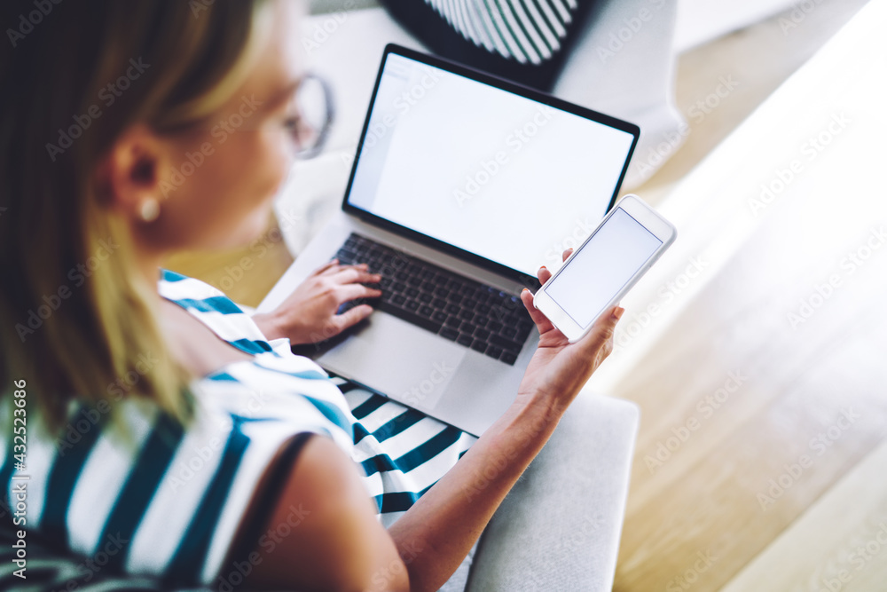 Woman watching funny video on smartphone while working on laptop Woman watching funny video on smartphone while working on laptop