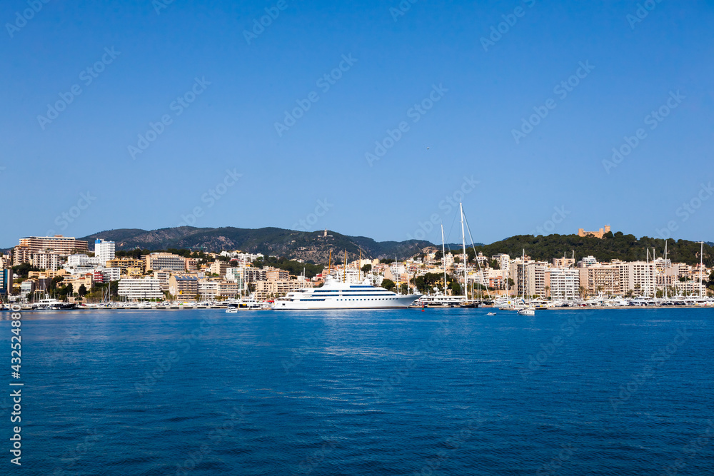 View of the bay of Palma de Mallorca with luxury yachts, buildings, mountains.