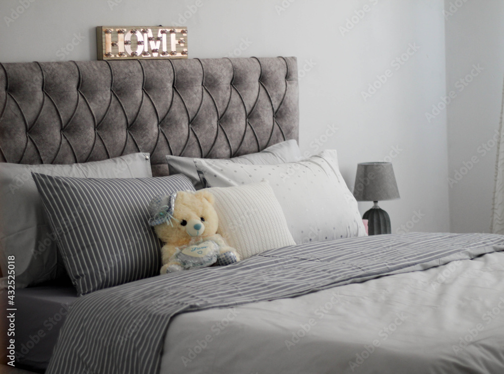 bedroom with grey set of bed and decorative teddy bear