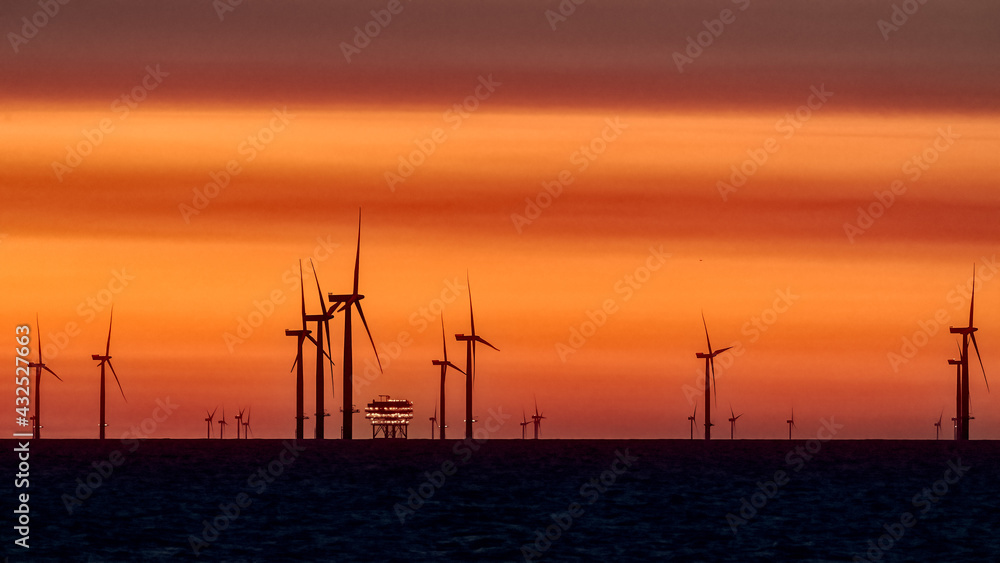 Obraz premium Offshore Wind Turbines and rig set against a sunrise red sky