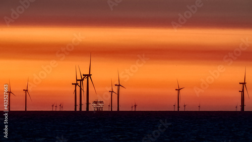 Offshore Wind Turbines and rig set against a sunrise red sky