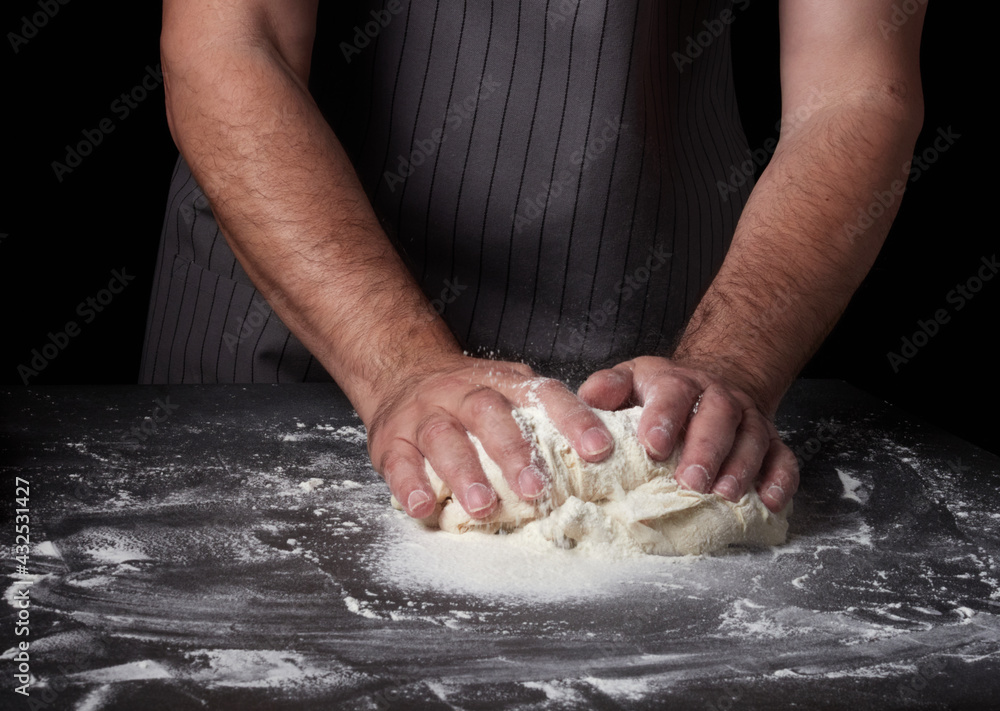 Baking concept. Hands roll dough on black kitchen table. Baker cooking pastry