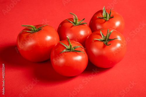 Juicy tomatoes on a bright red background. Fresh vegetables on a branch. Kitchen. background for restaurant.