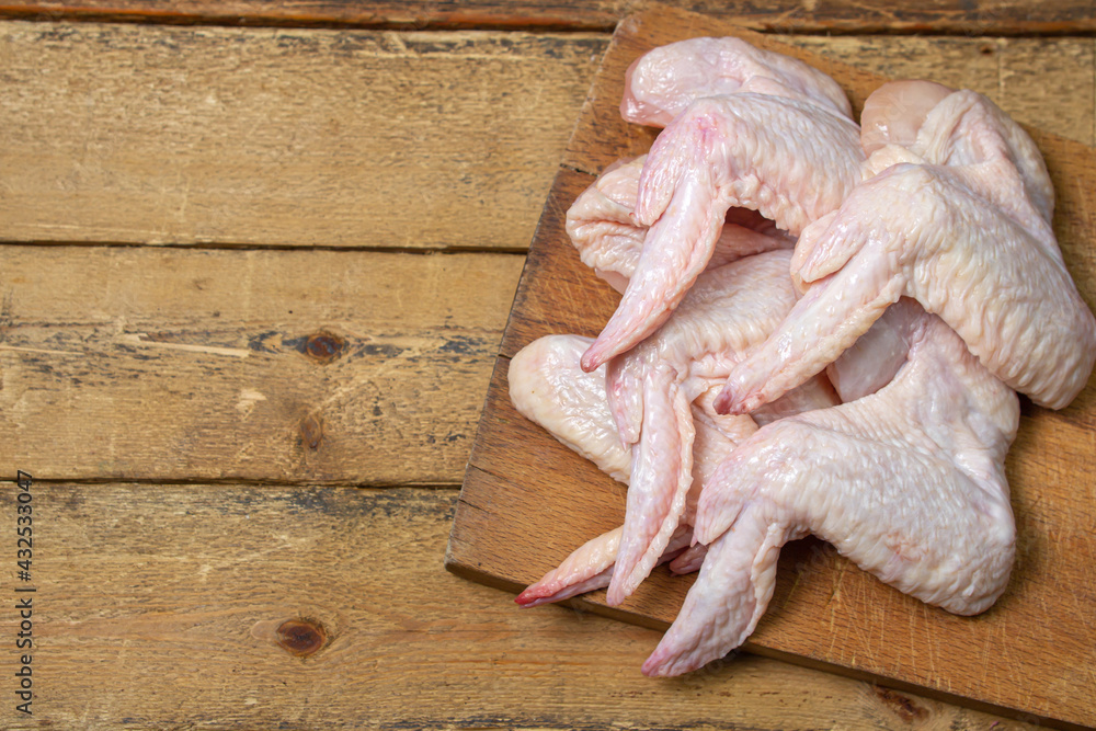 Fototapeta premium Raw chicken wings on a wooden background. Fresh chicken meat. Healthy diet.