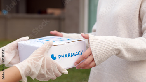 Fotografiet Asian female patient receive medication package box free first aid from pharmacy hospital delivery service at home wear glove in telehealth, telemedicine healthcare insurance online concept