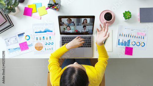 Top view of business woman talking about sale report in video conference. Asian team using laptop and tablet online meeting in video call.Working from home, Working remotely and Social isolation.
