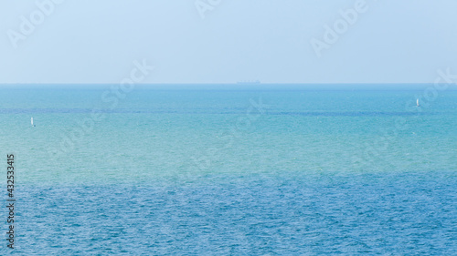 Landscape photo of sea or ocean with two of small white sailboat with clear blue sky.