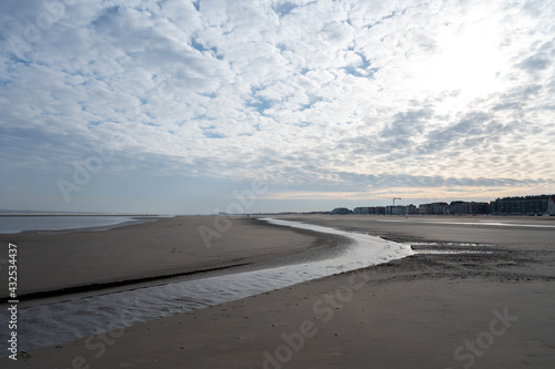Low tide period on yellow sandy beach in small Belgian town De Haan or Le Coq sur mer, luxury vacation destination, summer holidays