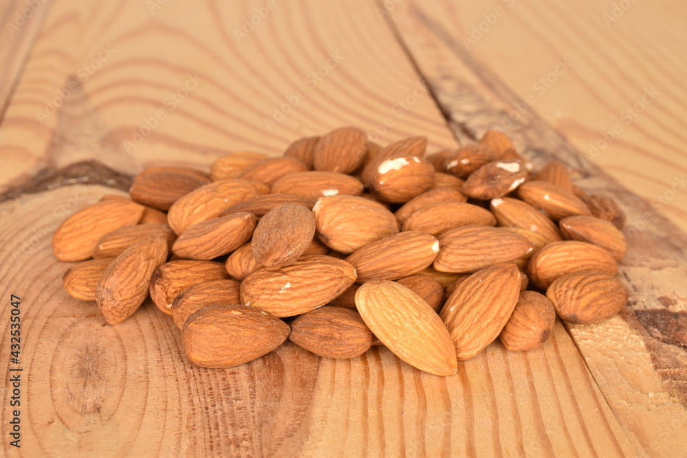 Several grains of peeled raw, organic almonds, close-up, on a wooden table. Several grains of peeled raw, organic almonds, close-up, on a wooden table.