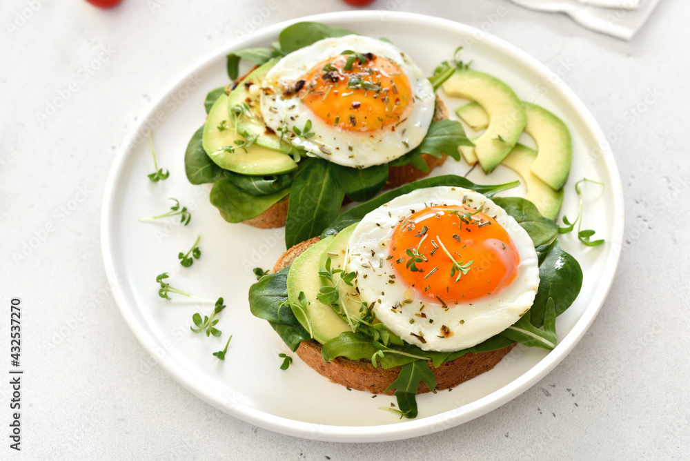 Fried eggs, avocado and greens on toasted bread