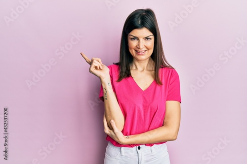 Young hispanic woman wearing casual clothes smiling happy pointing with hand and finger to the side © Krakenimages.com