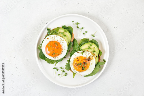 Fried eggs, avocado and greens on bread