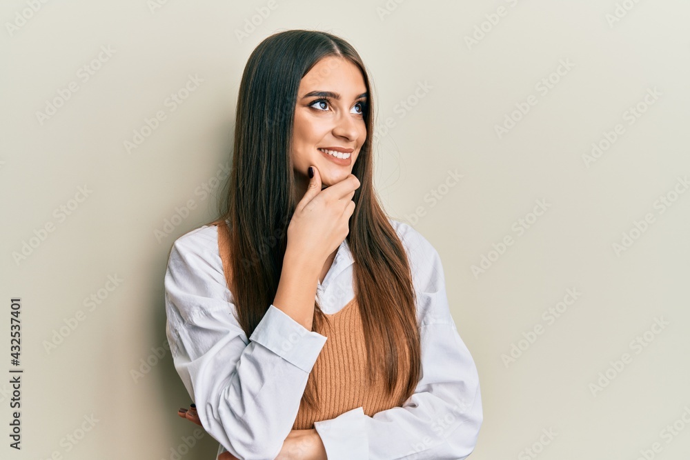 Beautiful brunette young woman wearing casual clothes with hand on chin thinking about question, pensive expression. smiling with thoughtful face. doubt concept. Beautiful brunette young woman wearing casual clothes with hand on chin thinking about question, pensive expression. smiling with thoughtful face. doubt concept.