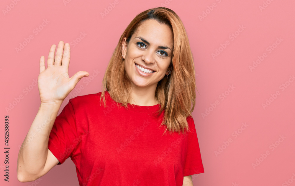 Hispanic young woman wearing casual red t shirt showing and pointing up with fingers number five while smiling confident and happy. Hispanic young woman wearing casual red t shirt showing and pointing up with fingers number five while smiling confident and happy.