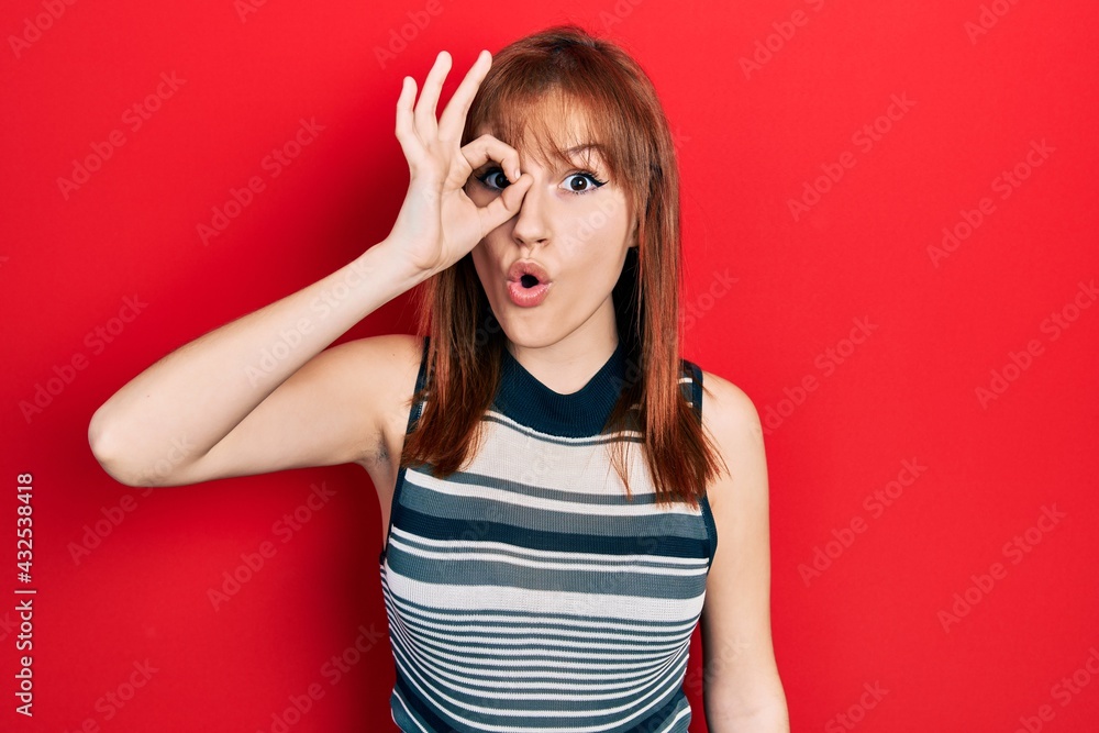 Redhead young woman wearing casual t shirt doing ok gesture shocked with surprised face, eye looking through fingers. unbelieving expression. Redhead young woman wearing casual t shirt doing ok gesture shocked with surprised face, eye looking through fingers. unbelieving expression.