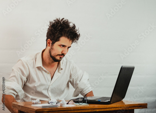 Fényképezés Young Caucasian male staring at the laptop, bored and disheveled during work