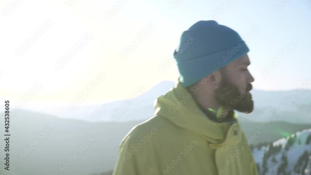 Slow panning shot of confident bearded man hipster overlooking mountains at sunrise . Concept of freedom and adventure Slow panning shot of confident bearded man hipster overlooking mountains at sunrise . Concept of freedom and adventure