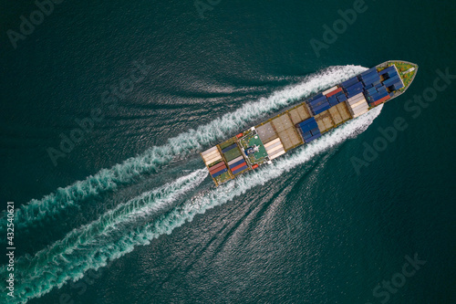 Aerial top view of cargo ship with contrail in the ocean sea ship carrying container and running for export from container international port to custom ocean concept freight shipping by ship service