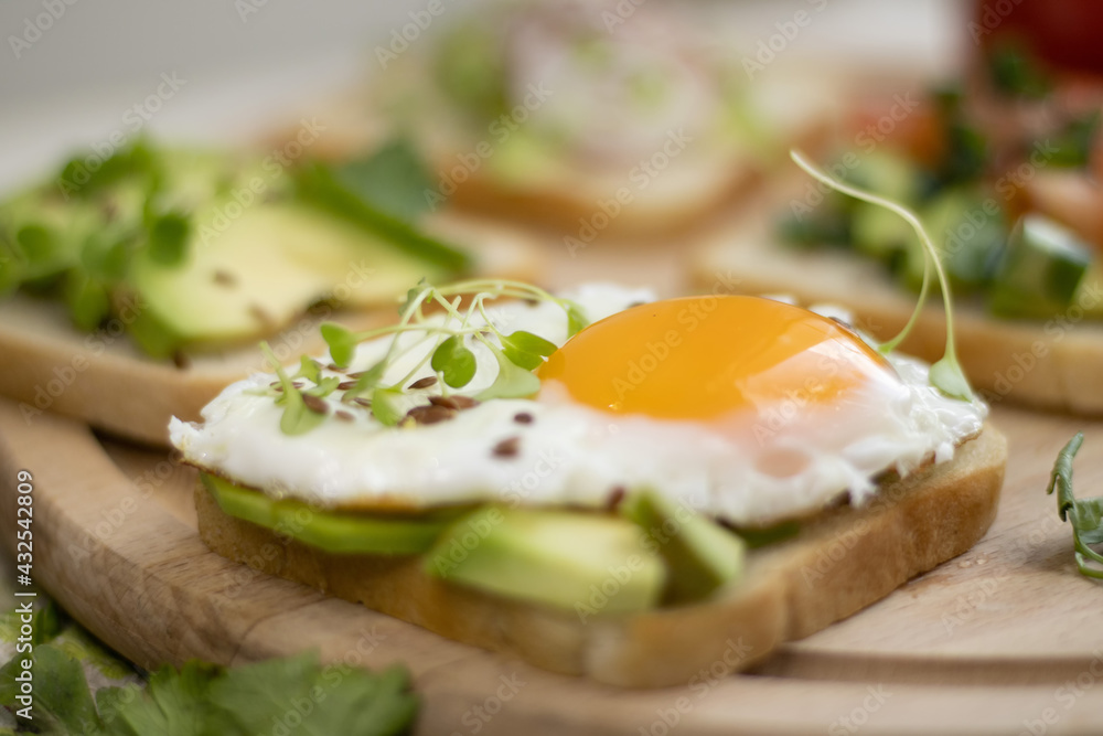 Fried Egg Avocado Sandwich - Sliced ​​avocado and egg on toasted bread with arugula for a healthy breakfast or snack.