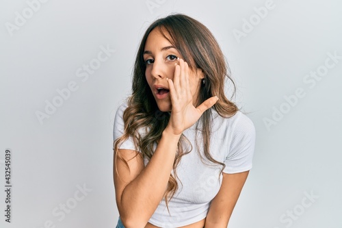 Young brunette woman wearing casual white t shirt hand on mouth telling secret rumor, whispering malicious talk conversation