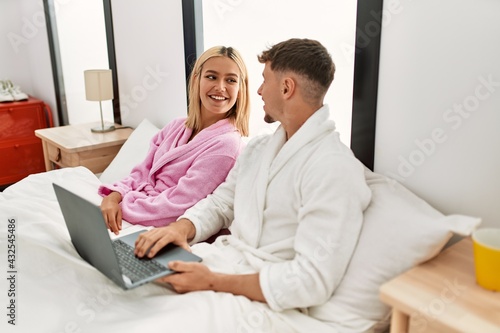 Young caucasian couple smiling happy using laptop sitting on the bed at home. © Krakenimages.com