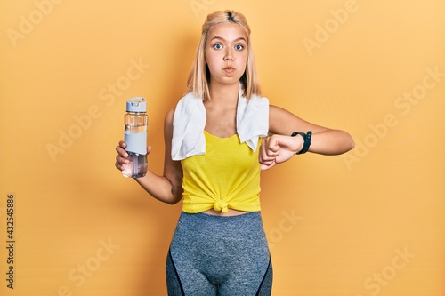 Beautiful blonde sports woman using smart watch puffing cheeks with funny face. mouth inflated with air  catching air.