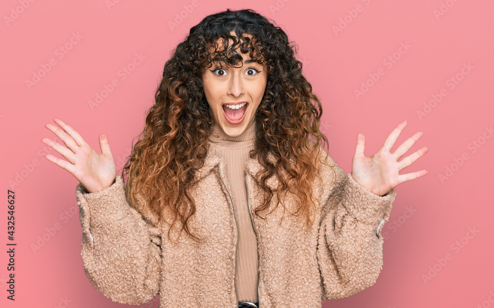 Young hispanic girl wearing winter clothes celebrating crazy and amazed for success with arms raised and open eyes screaming excited. winner concept Young hispanic girl wearing winter clothes celebrating crazy and amazed for success with arms raised and open eyes screaming excited. winner concept
