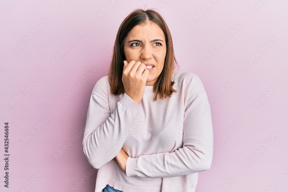 Young beautiful woman wearing casual clothes looking stressed and nervous with hands on mouth biting nails. anxiety problem. Young beautiful woman wearing casual clothes looking stressed and nervous with hands on mouth biting nails. anxiety problem.