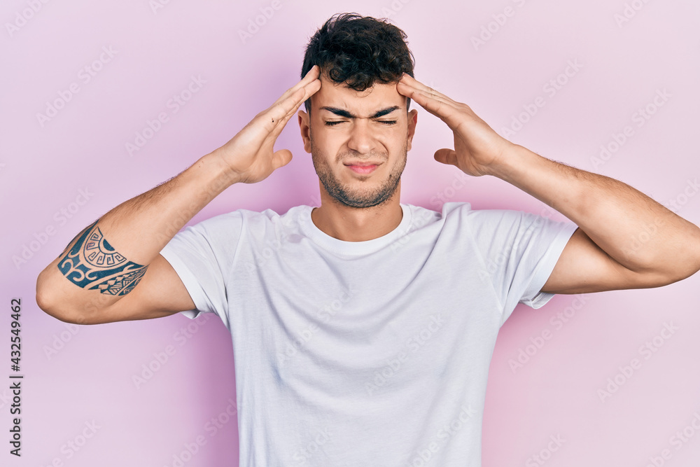 Young hispanic man wearing casual white t shirt with hand on head, headache because stress. suffering migraine. Young hispanic man wearing casual white t shirt with hand on head, headache because stress. suffering migraine.