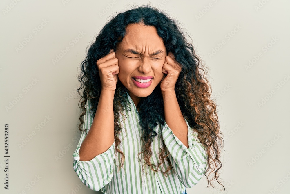 Young latin woman wearing casual clothes covering ears with fingers with annoyed expression for the noise of loud music. deaf concept.